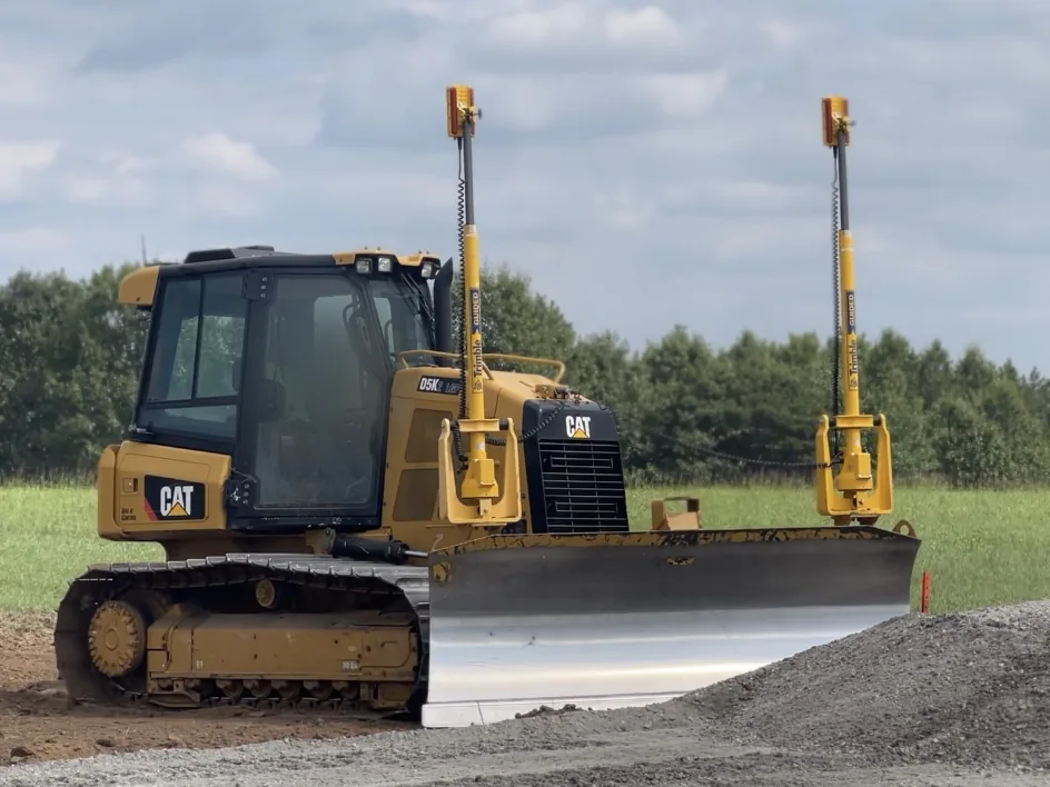 Dozer with GPS masts grading a gravel pad on a commercial site, civil construction