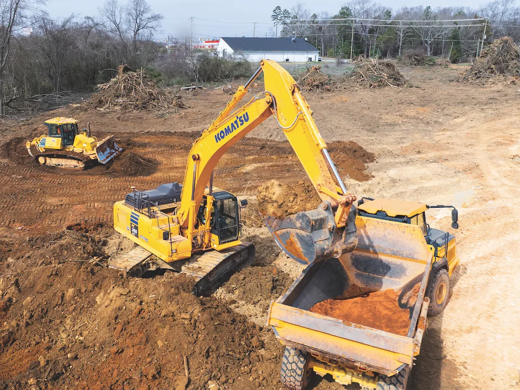 Excavator loading an articulated dump truck while a dozer grades the site behind it, excavation