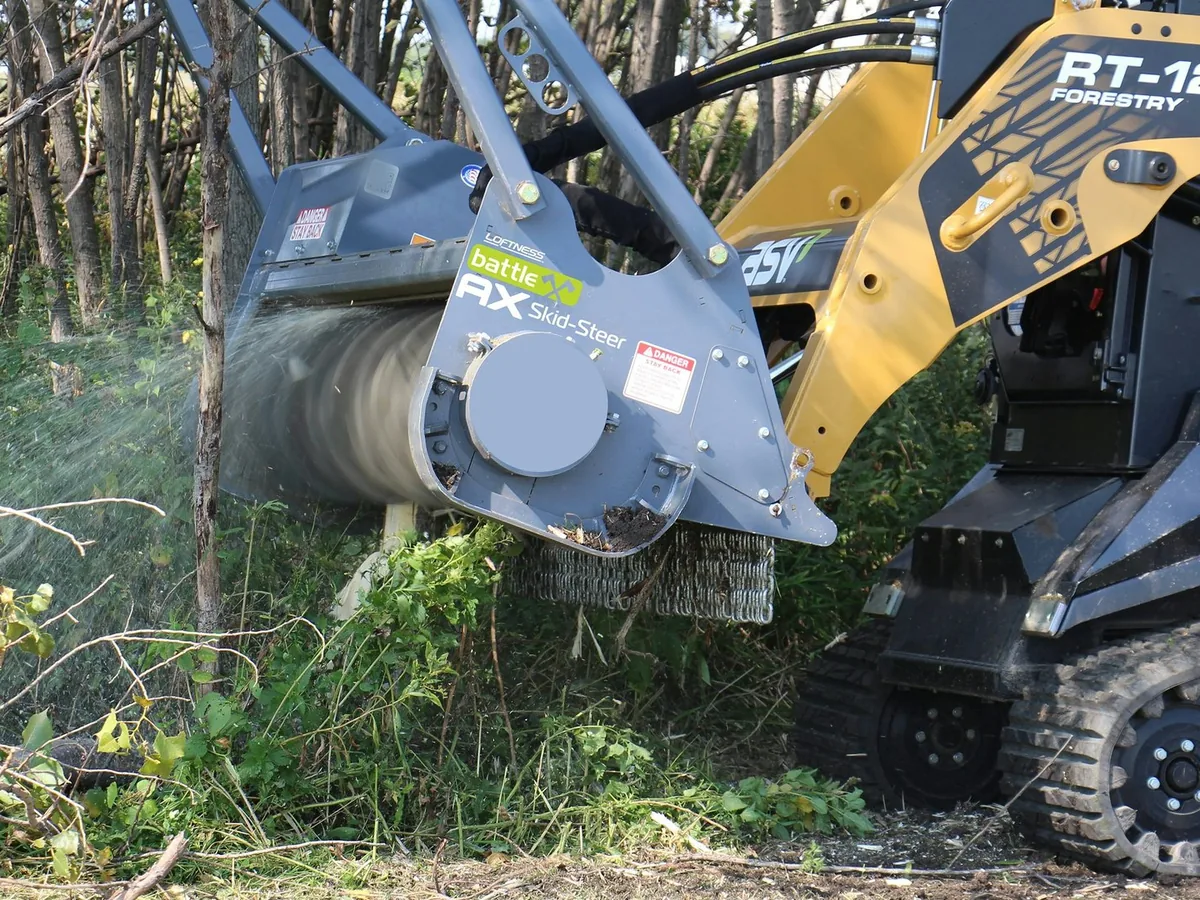 Mulching head grinding through brush and saplings with chips flying, forestry mulching