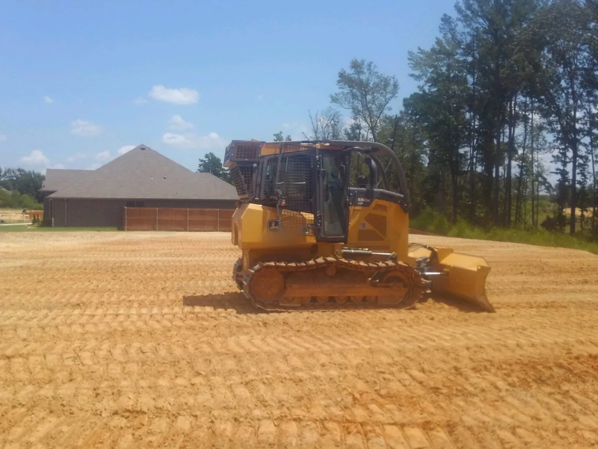 Crawler dozer grading a building lot smooth next to new houses, site preparation